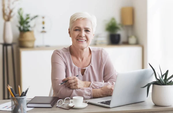 Uśmiechnięta babcia pracująca z laptopem w domu — Zdjęcie stockowe