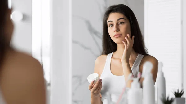 Chica del Milenio Aplicando Crema Facial Hidratante Piel en el Baño, Panorama — Foto de Stock