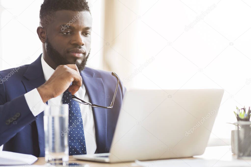 Close up of man in suit reading reports on laptop