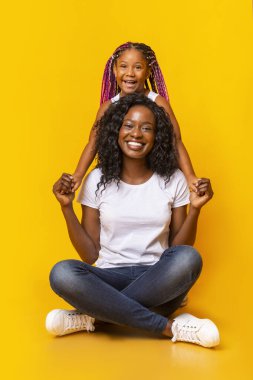 Güzel anne yerde oturup kızıyla el ele tutuşuyor.