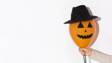 Yüzü çizilmiş turuncu balon ve kadın eli şapkalı.