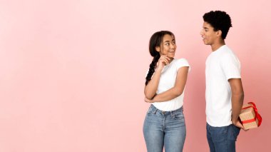 Sevgilisinden hediye saklayan mutlu adam, pembe arka plan.