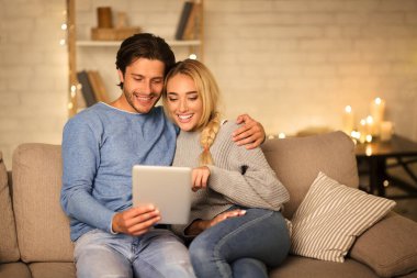 Sevgili eşler tabletten film seçer, evde birlikte dinlenirler.