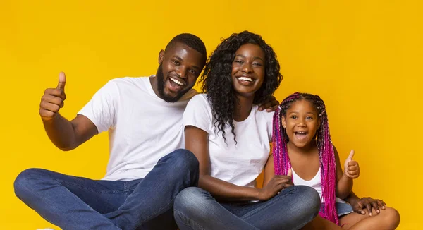 Gelukkige ouders en hun dochter die duimen laten zien, iets aanbevelen — Stockfoto