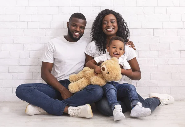Šťastná černošky rodina s malým synem sedí na podlaze spolu — Stock fotografie