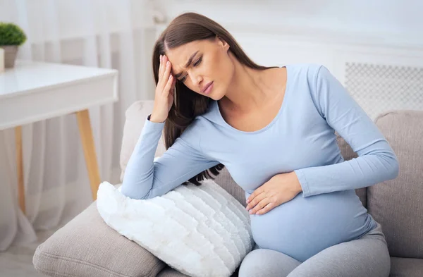 Ciąża Millennial Girl o ból głowy siedzi na kanapie w domu — Zdjęcie stockowe