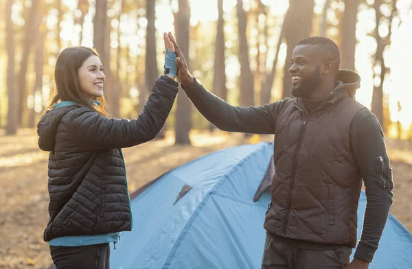 Negro chico dando chica alta cinco, camping en otoño bosque —  Fotos de Stock