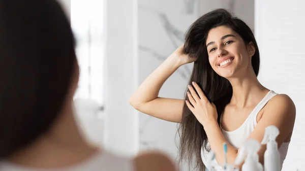 Flicka rörande hår ser i spegeln i badrummet, Panorama — Stockfoto