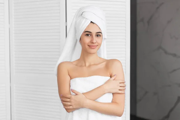Chica envuelta en toalla de pie sonriendo en la cámara en el baño — Foto de Stock