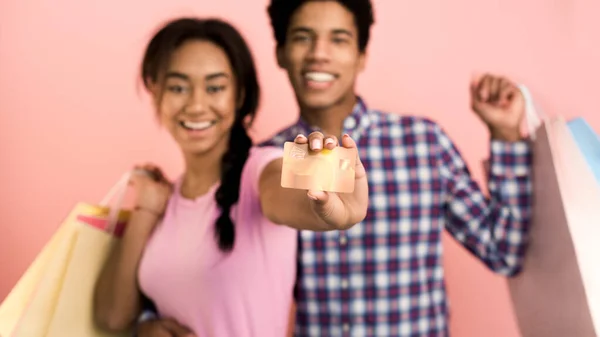 Pasangan yang gembira menunjukkan kartu kredit dan memegang tas belanja — Stok Foto