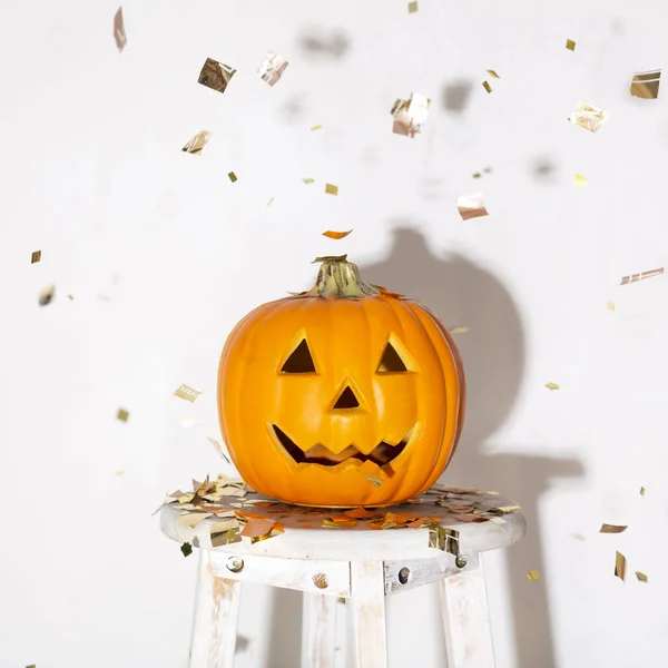 Calabaza naranja de Halloween con confeti de oro en blanco —  Fotos de Stock