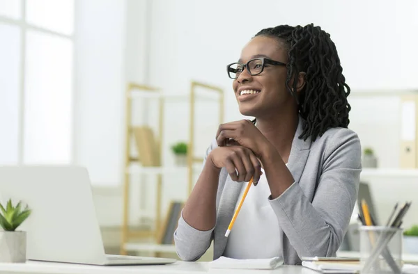 Sorridente nero affari signora seduta a computer portatile a luogo di lavoro — Foto Stock