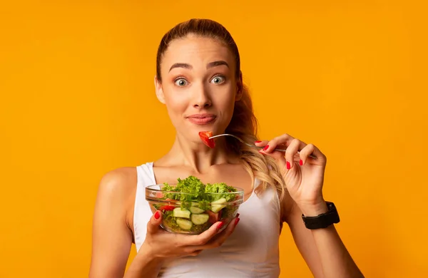 Überraschte Frau mit Gemüsesalat vor gelbem Studiohintergrund — Stockfoto