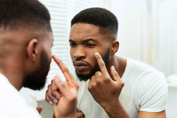 Genç Afrikalı bir adam yüzüne dokunuyor, kaliteli cildini inceliyor. — Stok fotoğraf