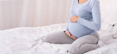 Yatak odasında, Panorama 'da, yatakta oturan tanınmayan hamile kadın.