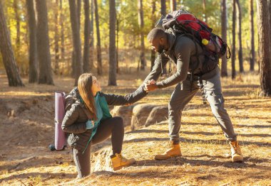 Nazik bir adam dağ ormanlarında yürürken kadına yardım ediyor.