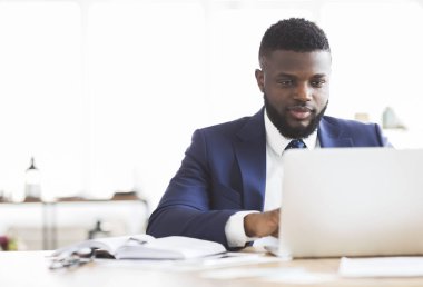 Ofiste dizüstü bilgisayarla çalışan konsantre iş adamı.