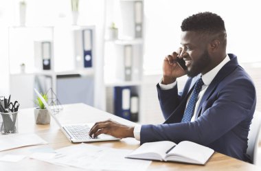 Neşeli genç girişimci iş ortağıyla cep telefonuyla konuşuyor.