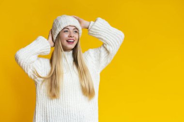 Örgü şapkalı, boş alana bakan keyifli genç bir kadın.