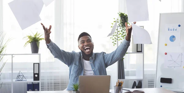 Alegre empleado afroamericano celebrando éxito tirando papeles en la oficina — Foto de Stock