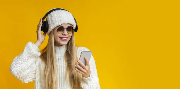 Usmívající se dívka v sluneční brýle a zimní klobouk sledování videa on-line — Stock fotografie