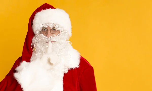 Babbo Natale su sfondo arancione tenendo il dito vicino alla bocca — Foto Stock