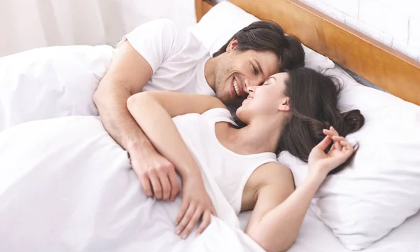 Alegre milenar homem e mulher acordando juntos na cama — Fotografia de Stock