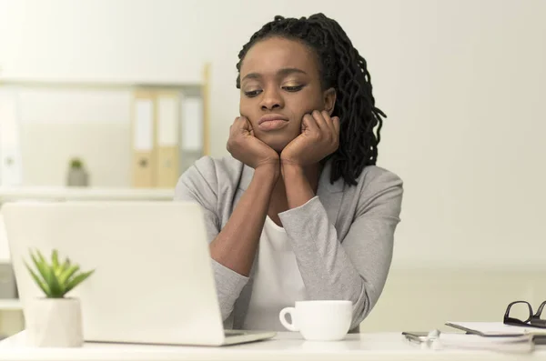 Aburrido negro Businesswoman mirando el ordenador portátil sentado en la oficina moderna — Foto de Stock