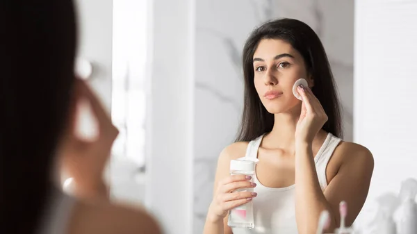 Ragazza che utilizza batuffolo di cotone che rimuove il trucco in piedi in bagno, Panorama — Foto Stock