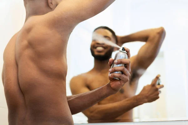ハンサムな無慈悲なアフリカ人男性を置く消臭剤でバスルーム — ストック写真