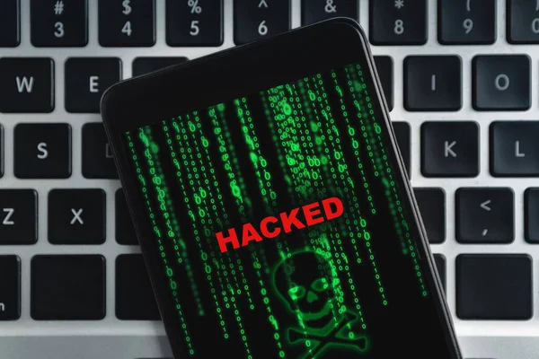 Zbliżenie hacked smartfona leżącego na klawiaturze laptopa — Zdjęcie stockowe