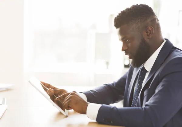 Jonge ondernemer die zakelijke toepassingen gebruikt op digitale tablet — Stockfoto