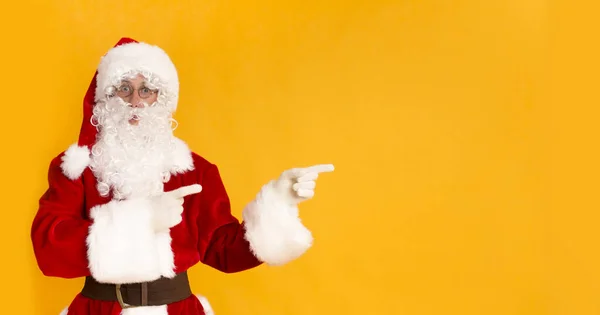Santa Claus pokazuje na przestrzeni kopii na żółtym tle — Zdjęcie stockowe