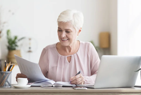 Volwassen redacteur die gedrukte tekst leest en notities maakt — Stockfoto