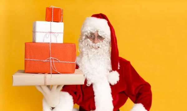 Santa Claus sosteniendo regalos de vacaciones en la mano en amarillo — Foto de Stock