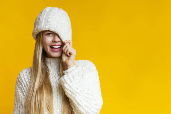 Lekfull flicka som täcker sitt öga med stickad hatt — Stockfoto