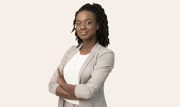 Афро-предпринимательница улыбается на камеру скрещивая руки поза, белый фон — стоковое фото