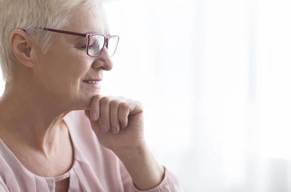 Nahaufnahme einer Seniorin mit Brille, die zu Hause liest — Stockfoto