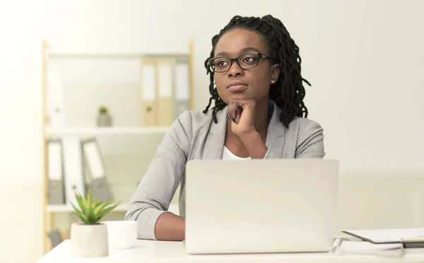 Nachdenkliche Unternehmerin sitzt am Arbeitsplatz und berührt das Kinn — Stockfoto