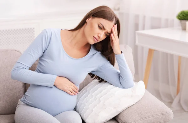 Pregnant Woman Suffering From Migraine Sitting On Couch At Home — Stock Photo, Image