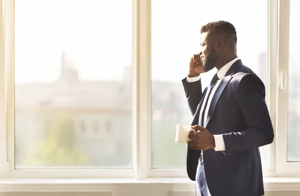 Homme d'affaires attrayant parlant sur smartphone et buvant du café près de la fenêtre — Photo