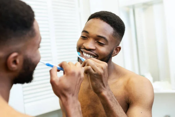 Millennial negro chico cepillarse los dientes en cuarto de baño — Foto de Stock