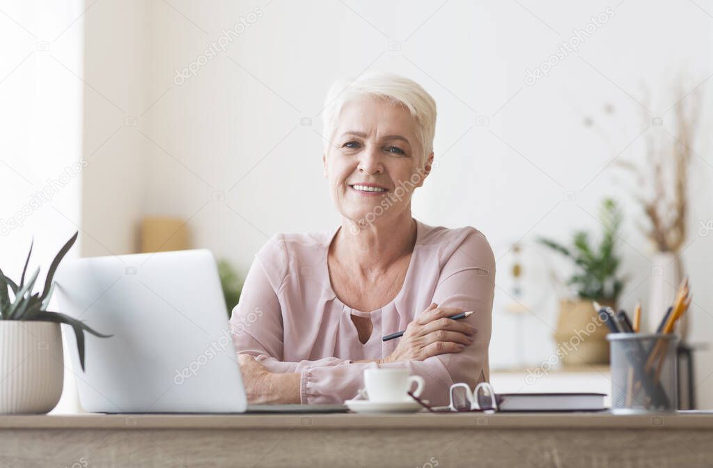 Attractive old lady posing at workdesk at home