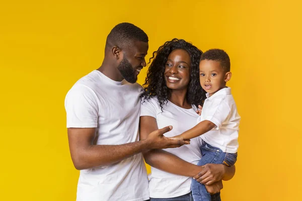 Portrét milujících rodičů s malým synem na žlutém pozadí — Stock fotografie
