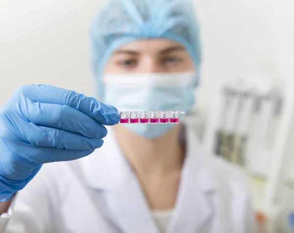 Female researcher doing investigations with colored test tubes — Stock Photo, Image