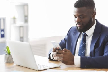 İş yerinde cep telefonu kullanan yakışıklı işadamı, e-posta gönderiyor