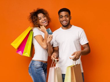 Mutlu Afrikalı çift alışveriş torbaları ve kredi kartı gösteriyor.