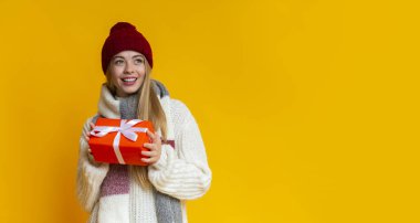 Çekici kız, sarı arka planda Noel hediyesini tutuyor.