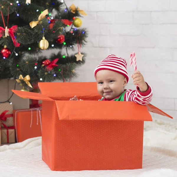 Šťastné dítě elf těší prázdninové lízátko ve velké dárkové krabici — Stock fotografie