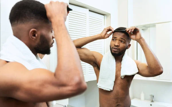 Impresionante afroamericano chico peinándose el pelo en el baño — Foto de Stock